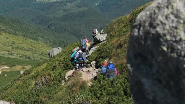 Un grup de turisti si copii cu rucsacuri coboara pe traseul de piatra din munte — Videoclip de stoc