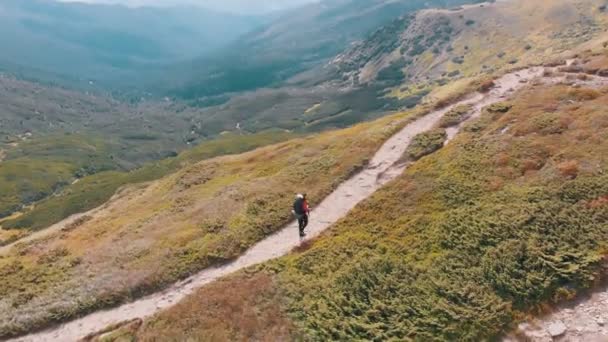 一个背负背包的旅行者沿着山坡爬山的空中风景.第2集 — 图库视频影像