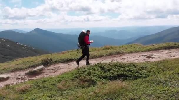 Vista aérea de un fotógrafo viajero con mochila Escalada por cordillera — Vídeo de stock