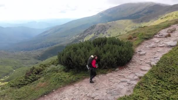 Vista aérea de un viajero con mochila Escalada a lo largo de la ladera de la montaña — Vídeo de stock