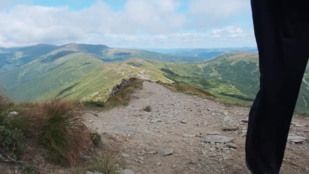 Turista con una mochila baja a lo largo del sendero de montaña de piedra en la colina — Vídeos de Stock