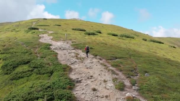 Vista aérea de un viajero con mochila Escalada a lo largo de la ladera de la montaña. Tiro épico — Vídeo de stock