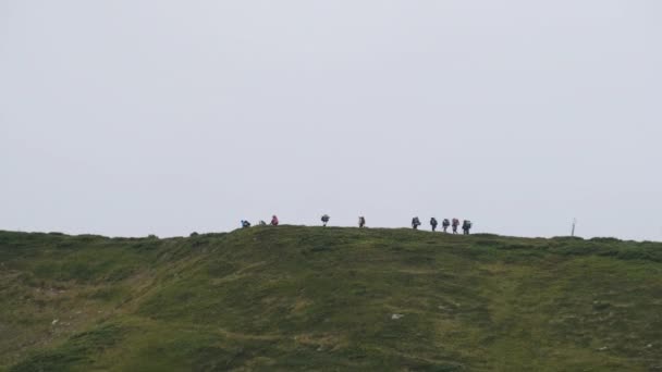 Grupa Turystów z plecakami wspina się na pasmo górskie. Widok z daleka — Wideo stockowe