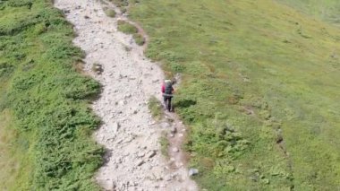 Sırt çantalı bir gezginin dağ yamacı boyunca tırmanış görüntüsü. Destansı Çekim