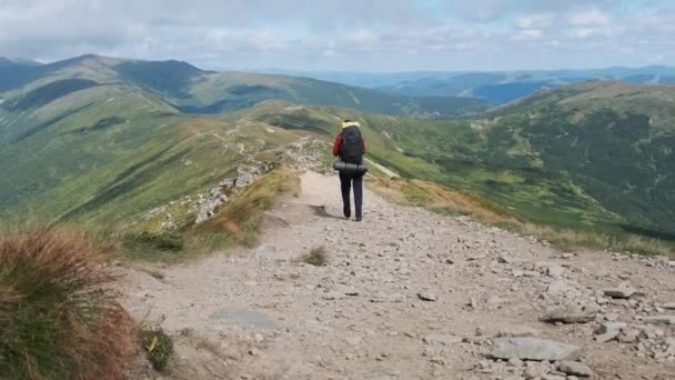 Turista com uma mochila desce ao longo da trilha da montanha de pedra na colina — Vídeo de Stock