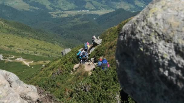 Gruppen av turister og barn med ryggsekker går ned på Stone Trail i fjellet – stockvideo