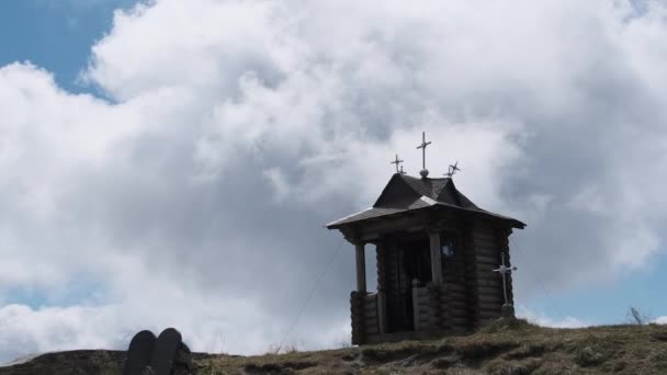Pequeña capilla de madera vieja en la cima de la montaña en el fondo Nubes móviles en el cielo. — Vídeo de stock