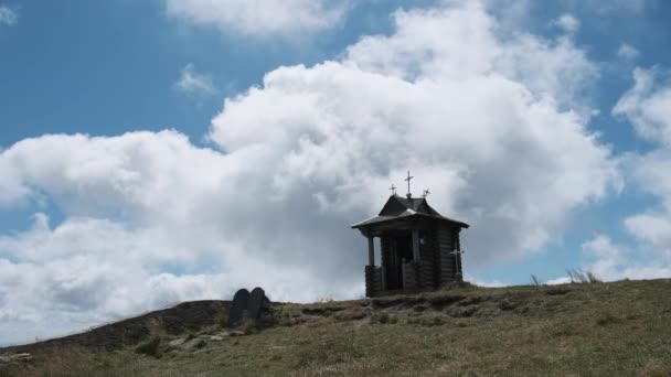 Liten gammal träkapell på toppen av berget på bakgrunden rörliga moln i himlen. — Stockvideo