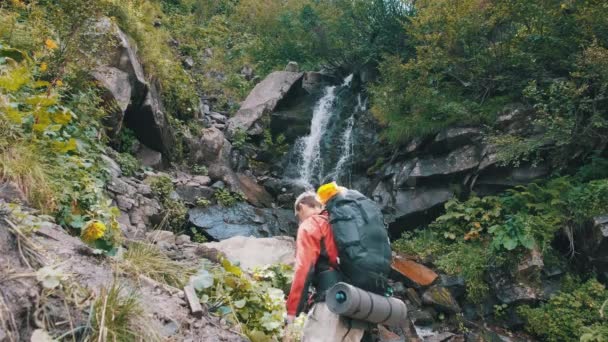 Turista hátizsák jött a hegyi vízesés és terjesztése karok oldalak — Stock videók