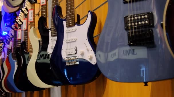 Guitare. Beaucoup de nouvelles guitares électriques multicolores sont accrochées dans un magasin de musique — Video