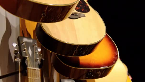 Guitare. Beaucoup de nouvelles guitares acoustiques multicolores sont accrochées dans le magasin de musique — Video