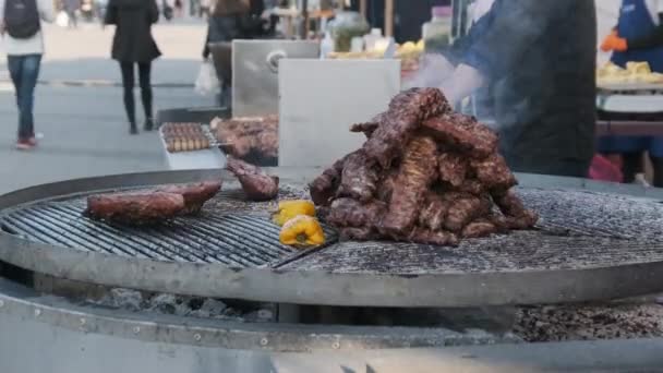Grandes cortes de carne de res se cocinan en la parrilla giratoria al aire libre en Street Food Festival — Vídeo de stock