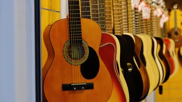 Магазин гитар. Много новых разноцветных акустических гитар висят в музыкальном магазине — стоковое видео
