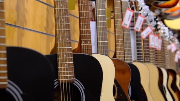 Магазин гитар. Много новых разноцветных акустических гитар висят в музыкальном магазине — стоковое видео