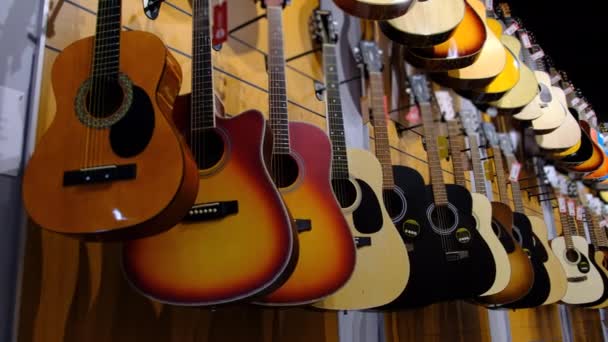 Tienda de Guitarra. Muchas nuevas guitarras acústicas multicolores se cuelgan en la tienda de música — Vídeo de stock