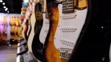 Gitar Dükkanı. Birçok yeni renkli elektro gitar bir müzik mağazasında asılı duruyor.