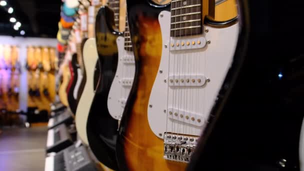 Магазин гитар. Много новых разноцветных электрогитар висят в музыкальном магазине — стоковое видео