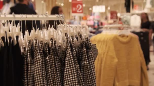 Loja de roupas. Roupas femininas penduradas em cabides dentro da loja. — Vídeo de Stock