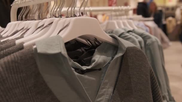 Klädaffär. Kvinnors kläder hänger på Hangers inne i butiken. — Stockvideo
