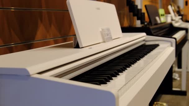 Loja de música. Muitos grandes pianos elétricos e sintetizadores são vendidos na janela da loja — Vídeo de Stock