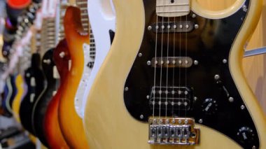 Gitar Dükkanı. Birçok yeni renkli elektro gitar bir müzik mağazasında asılı duruyor.