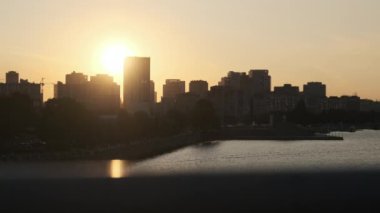 Çok katlı binaların siluetleriyle Büyük Şehir Embank 'inin üzerinde gün batımı