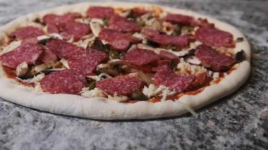 Parçalanmış İçindekilerle İştah açıcı Çiğ Pizza Hamuru Mutfak yüzeyinde yatıyor.