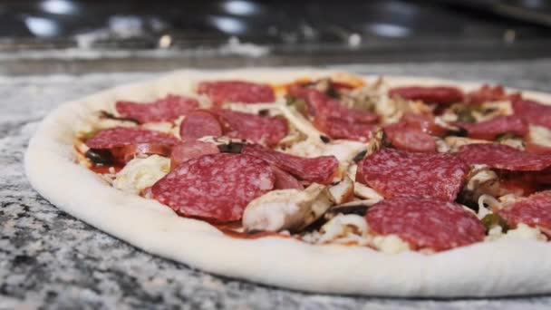 Plat à pizza cru appétissant avec des ingrédients hachés repose sur la surface de la cuisine. — Video