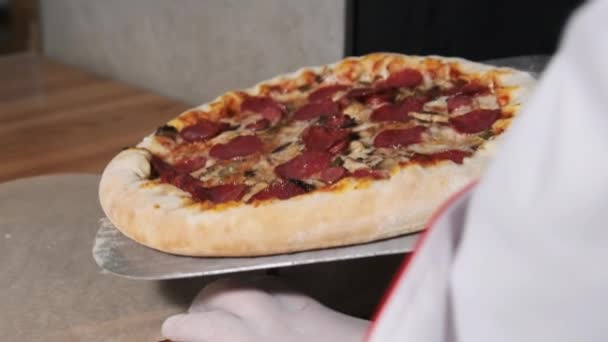 Szef kuchni używa Spatula do umieszczenia gotowej pizzy z piekarnika na stole — Wideo stockowe
