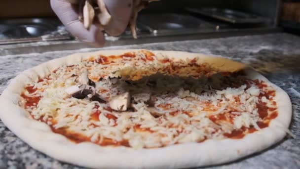 La mano del chef lanza deliciosamente los champiñones en rodajas sobre la pizza. Moción lenta — Vídeo de stock