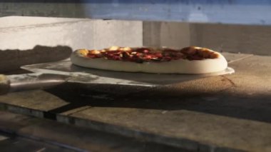 Şef restorandaki pizzayı fırından çıkarmak için bir Spatula kullanıyor.