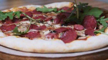 Beyaz eldivenli şef bitirilmiş pizzanın üzerine roka yaprakları koyar. Yeşillik ekliyorum. Yavaş Hareket