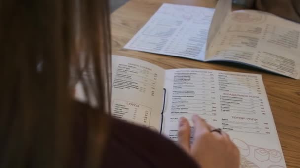 Voltar Vista de uma mulher lendo um menu em um restaurante. Estilo de vida. — Vídeo de Stock