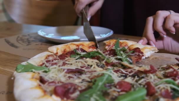 Kvinnliga händer tar en bit av pizzan från en träplatta i restaurangen. Långsamma rörelser — Stockvideo