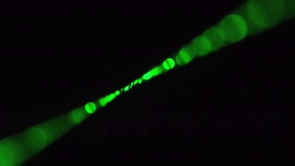 Gröna laserstrålen på svart bakgrund. Kraftlaserstråle skiner i dimma — Stockvideo