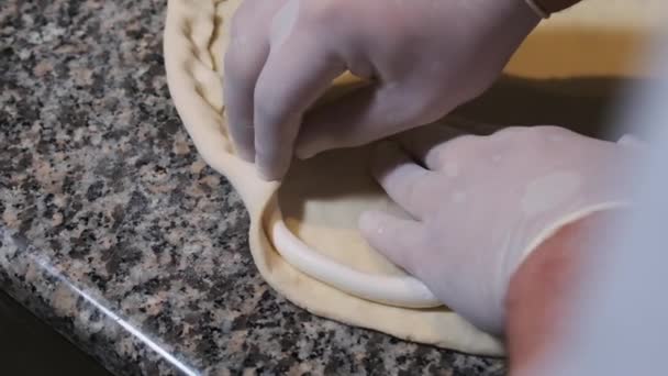 Chefs mains dans les gants Enveloppez la bordure du fromage dans la pâte à pizza crue. Mouvement lent — Video