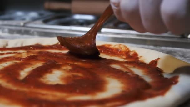 Chef Adicionando molho de tomate usando colher e espalhando na massa de pizza. Movimento lento — Vídeo de Stock