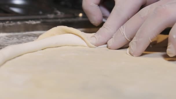 Kockar händer i handskar linda ostkanten i Raw Pizza Dough. Långsamma rörelser — Stockvideo