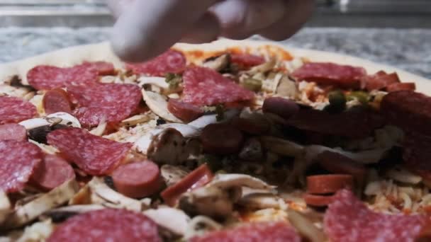 シェフの手はおいしいスライスされたサラミソーセージをピザに置きます。スローモーション — ストック動画