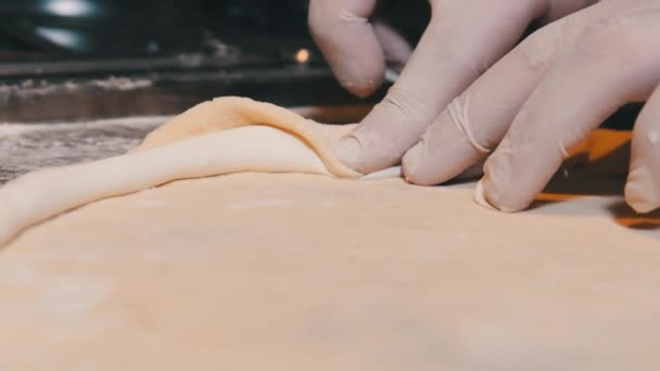 Köche Hände in Handschuhen wickeln den Käserand in den rohen Pizzateig. Zeitlupe — Stockvideo