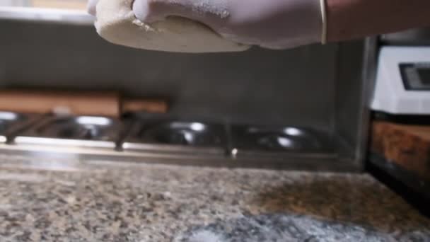 Una mano de chef con un guante blanco lanza una bola de masa cruda sobre la harina en cámara lenta — Vídeos de Stock