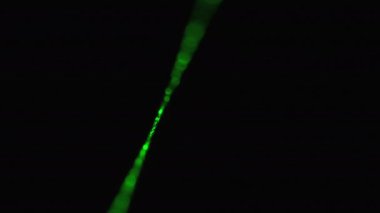 Siyah arka planda yeşil lazer ışını. Siste parlayan lazer ışını.