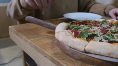 Restorandaki ahşap tabaktan pizzadan bir dilim alan kadın elleri. Yavaş Hareket