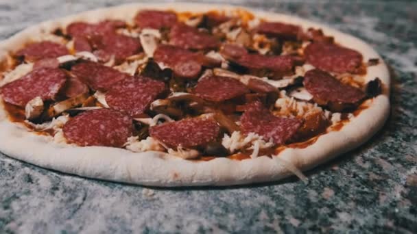 Apetitiva masa de pizza cruda con ingredientes picados se encuentra en la superficie de la cocina. — Vídeo de stock