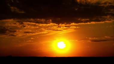 Bu zaman dilimi, altın güneş ufuk çizgisinin altına batarken güzel bir gün batımı yakalıyor. Karanlık, dramatik bulutlar tepemizde süzülür. Birkaç kuş alacakaranlıkta canlı, ateşli turuncu gökyüzünde uçar..