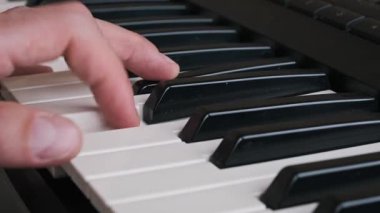 Sentezleyiciyle dinamik riff çalan bir bestecinin yakın plan görüntüsü. Müzisyen yaratıcı bir müzik seansında doğaçlama bir melodi uyduruyor, notaları ve akorları keşfediyor..