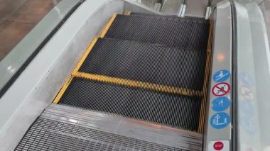 Yukarıdan bakıldığında, insan bacakları ve ayakları aşağı doğru gitmek için yürüyen bir yürüyen merdivene basıyor. Sahne, modern kentsel taşıma, yolcu hareketi ve toplu taşıma.