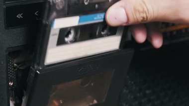 Elle çalışan klasik müzik kutusunu kapat, kaseti mavi etiket ile fırlat ve yeniden yerleştir, sonra güverteyi kapat ve oynat düğmesine bas, 80 'lerin analog ses ekipmanının nasıl kullanıldığını göster.