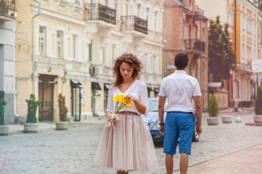 Mutlu kız sarı Gerber çiçek bir buket ile şehir etrafında yürür