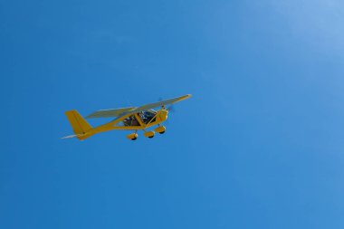 Mavi gökyüzünde ışık sarı uçak uçar